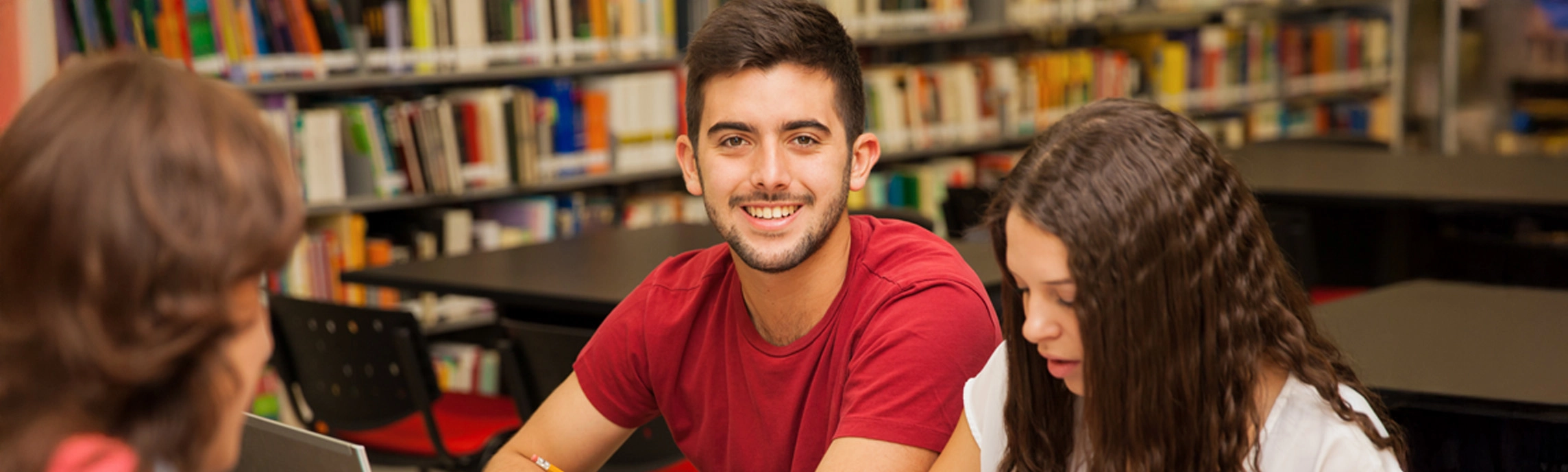 Un joven y una joven posando con sus libros de la serie Speak Your Mind frente a una pantalla con el logo de Roosevelt English Institute.